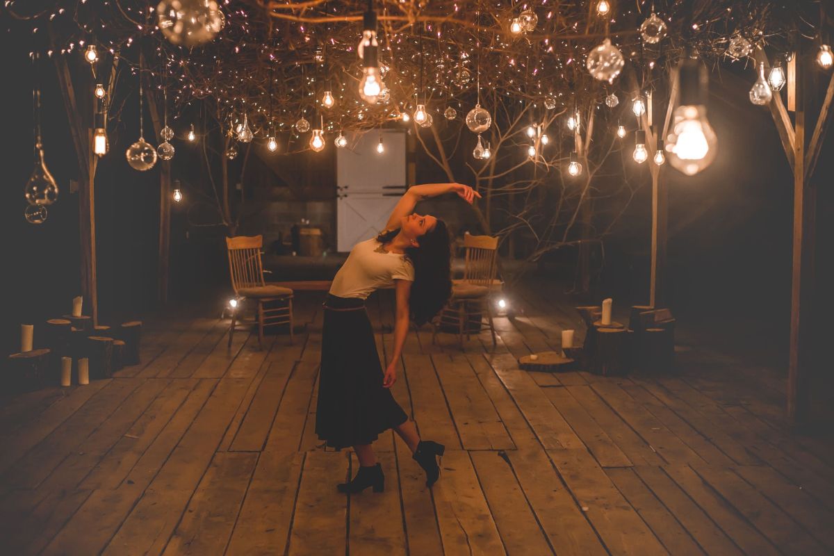 kobieta tańcząca na tarasie pośród oświetlonych lamp